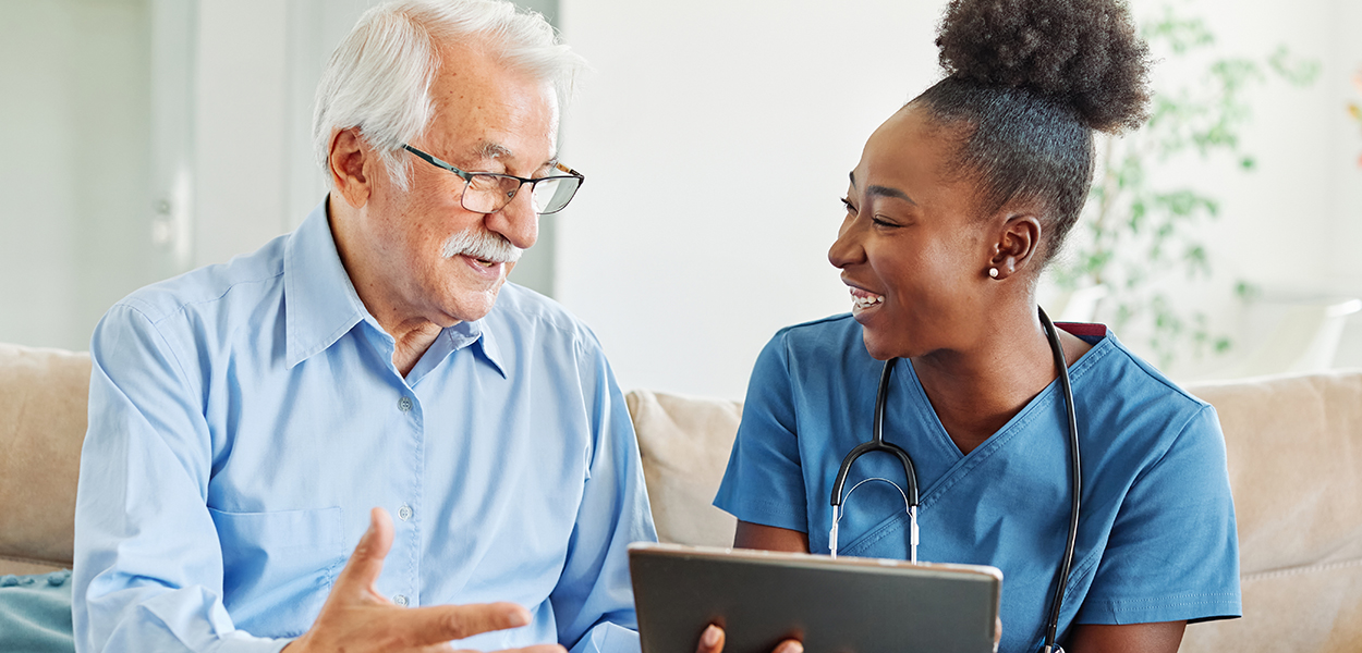 Image of nurse holding tablet next to an elderly person.