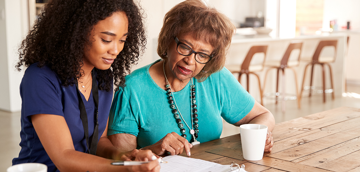 Image of nurse and elderly person going over paperwork.